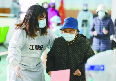 3月22日，鼓楼区江东街道龙江小学核酸检测点，“江将好”青年志愿者在帮助行动不便的老人。 通讯员 张春阳 南京日报/紫金山新闻记者 徐琦 摄