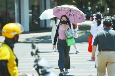 昨天，市民撑伞走在珠江路街头。当天，南京市气象台继续发布高温红色预警信号，全市部分街道最高气温升至40℃以上。 南京日报/紫金山新闻记者 徐琦 摄