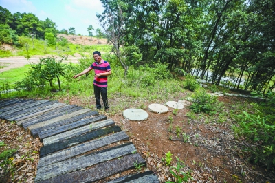 南京雨花石家乡园田公司王道林用废弃火车枕木和农村传统磨盘铺设了象征中国发展的农业和工业之路。