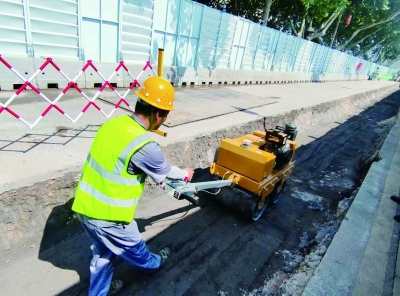 在雨花路供水管道改造项目现场，胡传平冒着高温压实路面。南京日报/紫金山新闻记者 张恺 摄