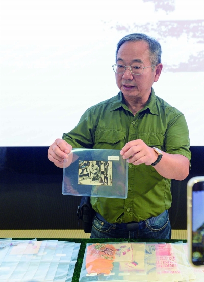 美籍华人鲁照宁展示捐赠的重要历史瞬间照片，记录了1945年9月2日日本向盟国投降签字仪式的场景。南京日报/紫金山新闻记者 孙中元 摄