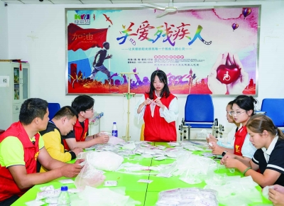 招宇环教残疾人制作简易手工，帮助他们再就业。