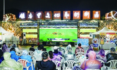 十月十八日晚，“苏超”半决赛南京队主场迎战泰州队。尽管天气降温明显，天空持续小雨，位于银杏里文化艺术街区的“苏超”第二现场人气依旧爆棚，市民热情观赛。 南京日报/紫金山新闻记者 戚珂嘉 摄