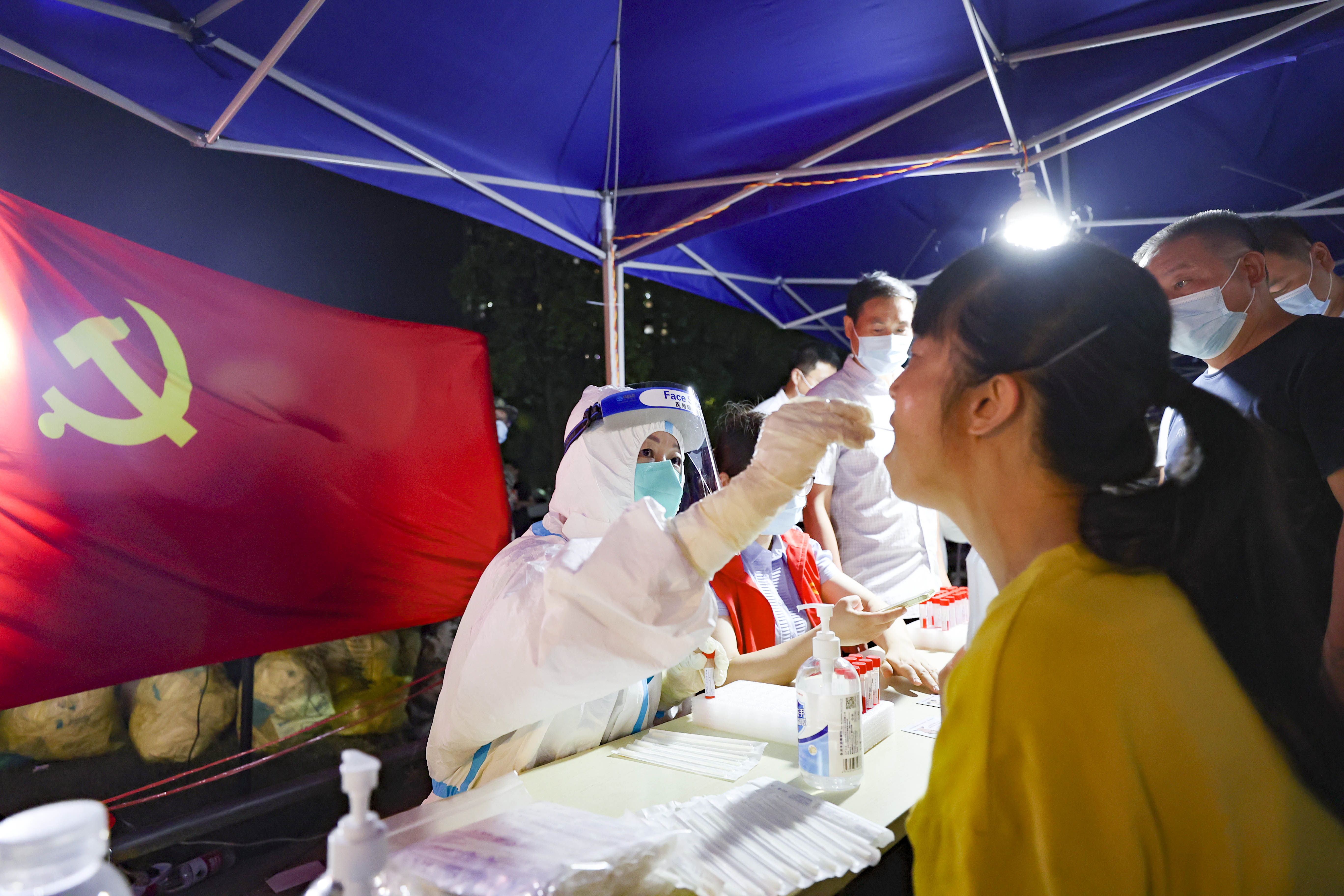 7月21日晚，雨花台区古雄街道党员干部正协助医务工作者开展核酸检测工作。据了解，雨花台区抽调452名“英雄支部”党员干部冲锋一线协助开展核酸检测志愿服务。南报融媒体记者 冯芃摄