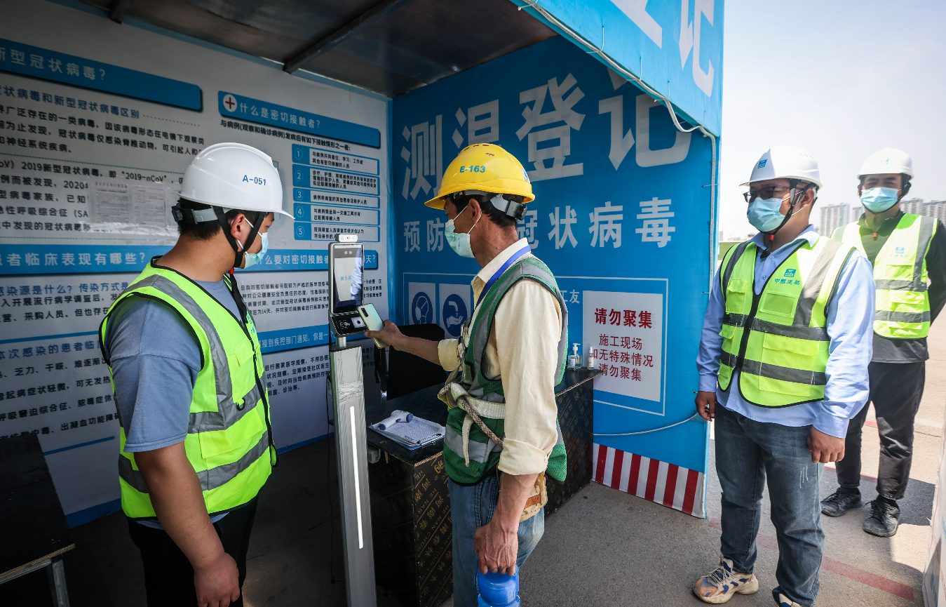 南部新城中建二局承建金陵华夏中心项目施工现场，在员工通道出入口，有专门人员正在值守，工人佩戴口罩和安全帽，经过测量体温、检查行程码和苏康码等，并进行实名登记后有序进入工地。南京日报/紫金山新闻记者 董家训