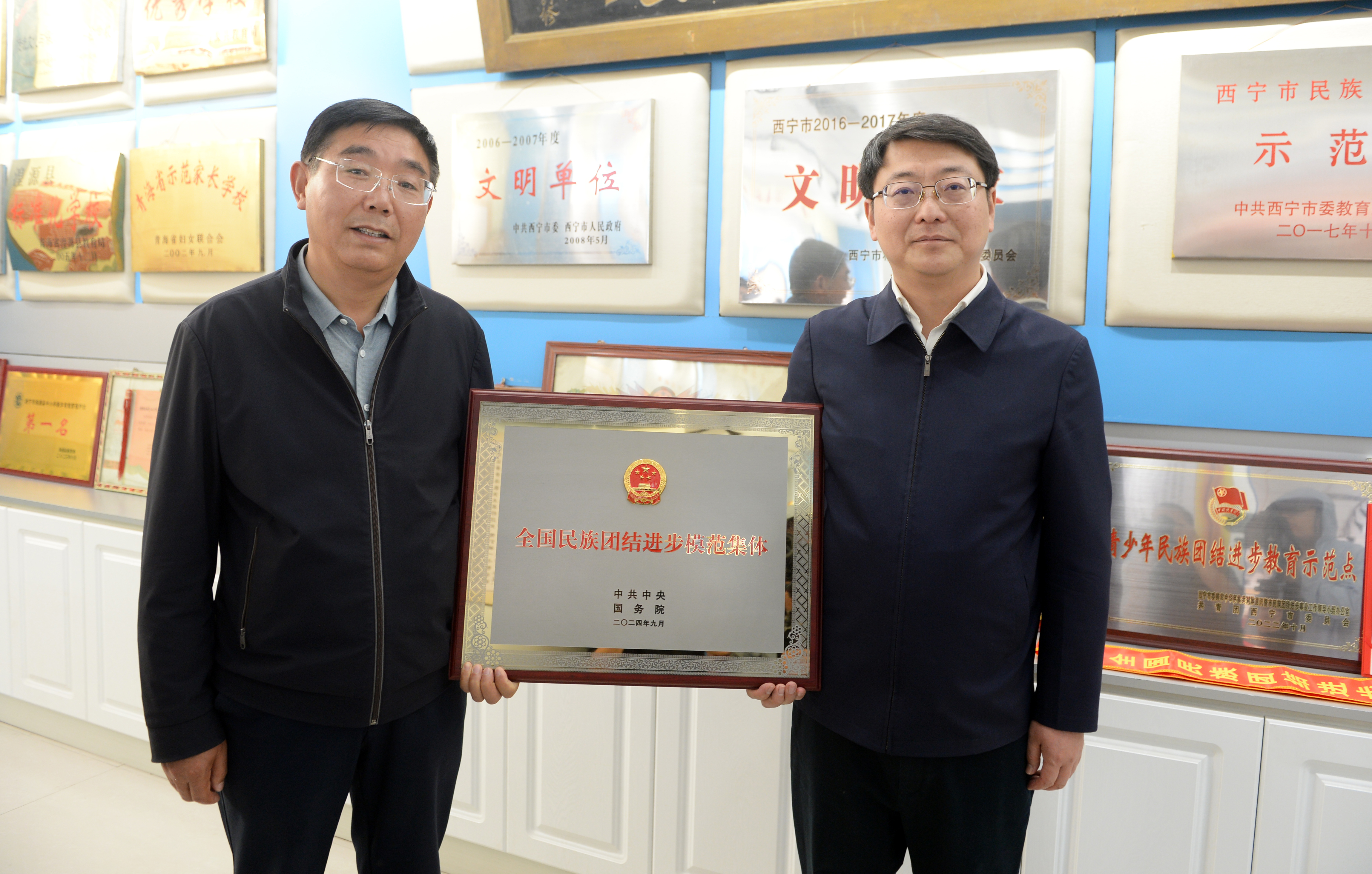 南京对口帮扶西宁工作组组长、西宁市政府副秘书长刘博（右）和湟源县城关一小校长薛忠共同展示“全国民族团结进步模范集体”奖牌。
