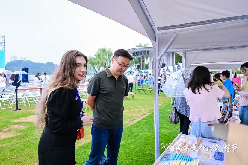 “Hello南京·读‘宁’千遍不厌倦”2025南京文化旅游节启动仪式现场，外国游客在文旅市集前驻足。