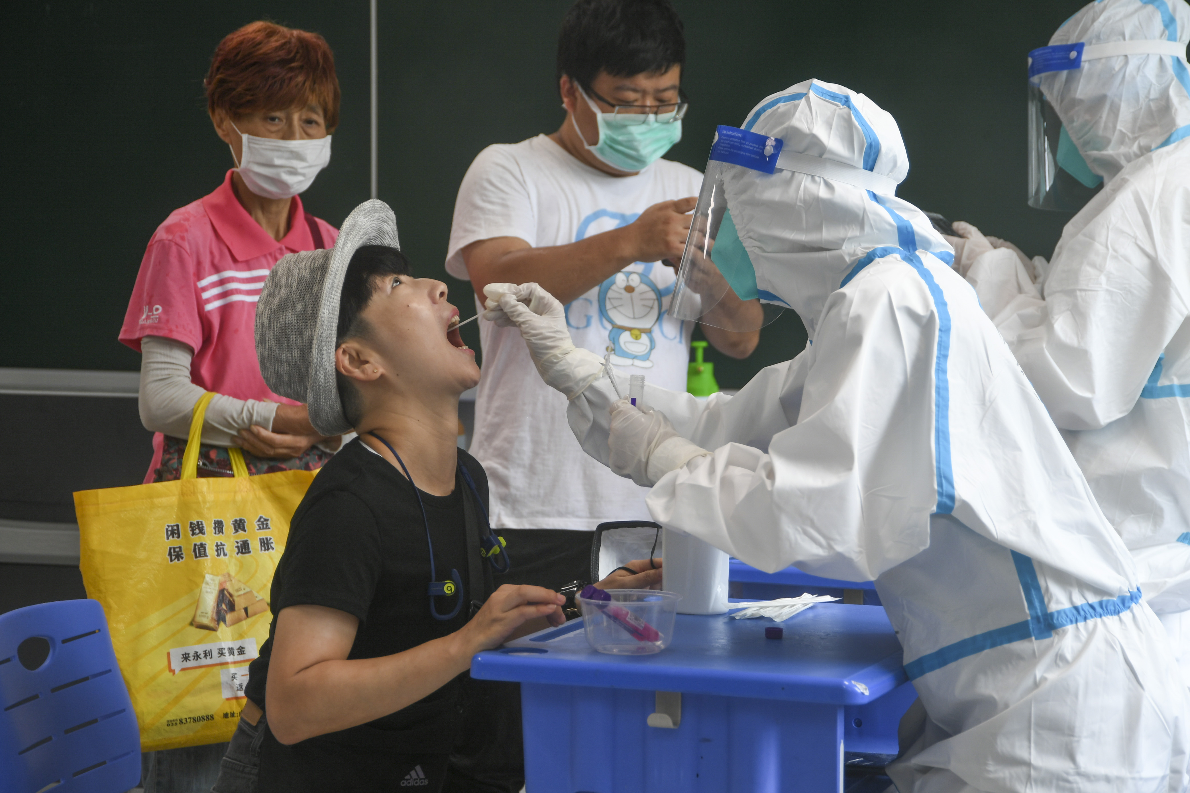 7月26日,在玄武外国语学校附属小学核酸采样点,来自镇江市的医护人员